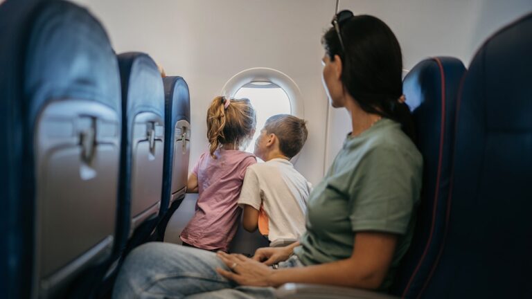 children-looking-plane-window-mother-seated.jpg