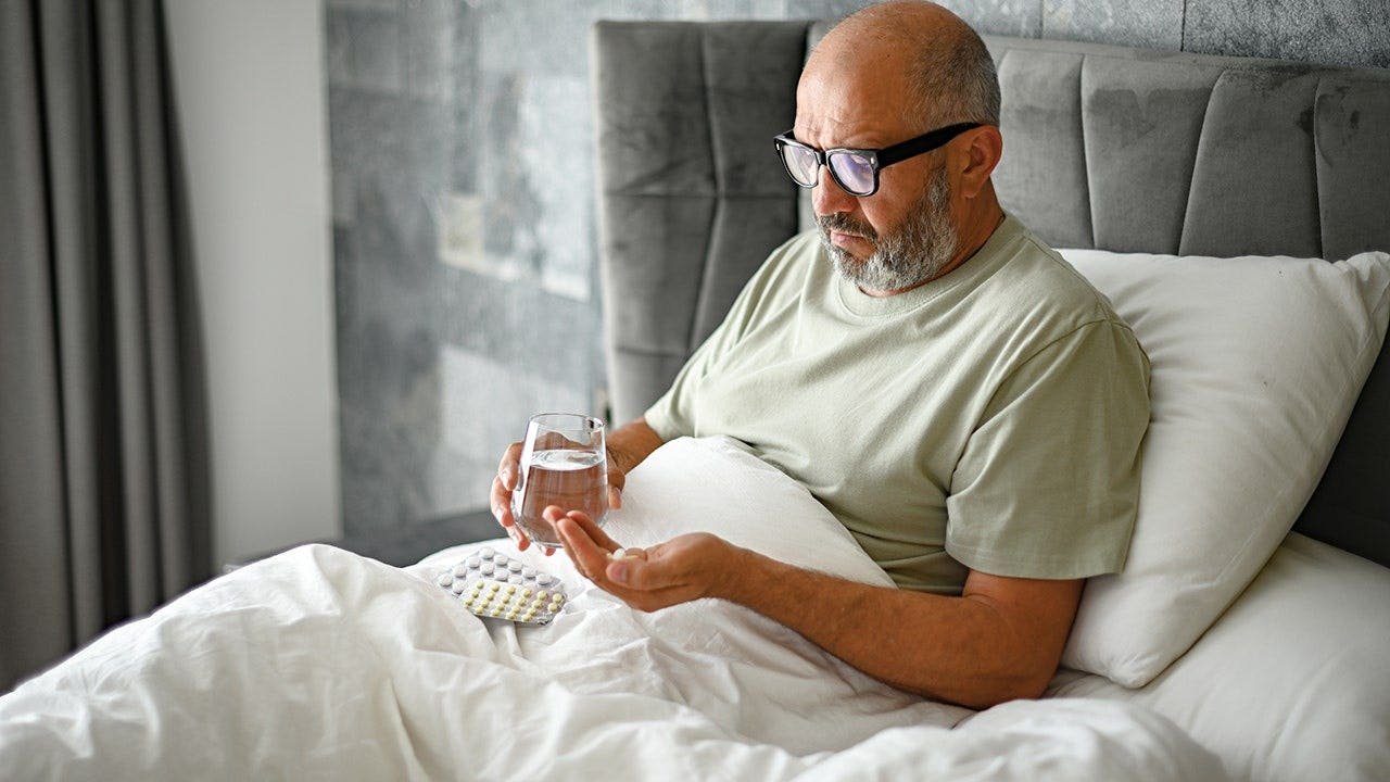 man-taking-medication-bed.jpg